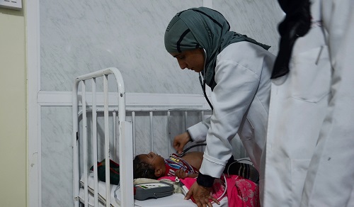 MSF ER doctor checking a child having trouble breathing.