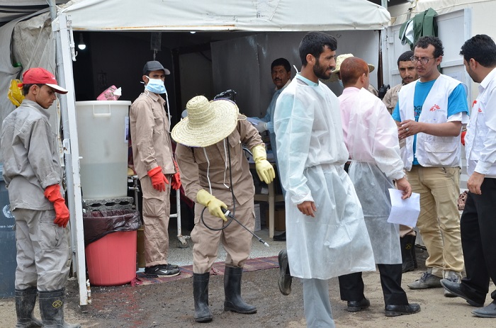MSF cleaner while spreading chlorination at the shoes of one of the nurses as he was getting out of the cholera treatment center. This is one of the precautions taken to prevent the spread of the cholera outside the center. Photo: Nuha Haider/MSF