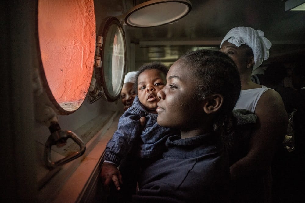 A woman and her baby look through a porthole on the Aquarius, a rescue vessel operated jointly by MSF and SOS MEDITERRANEE to assist people in distress in the Mediterranean Sea.