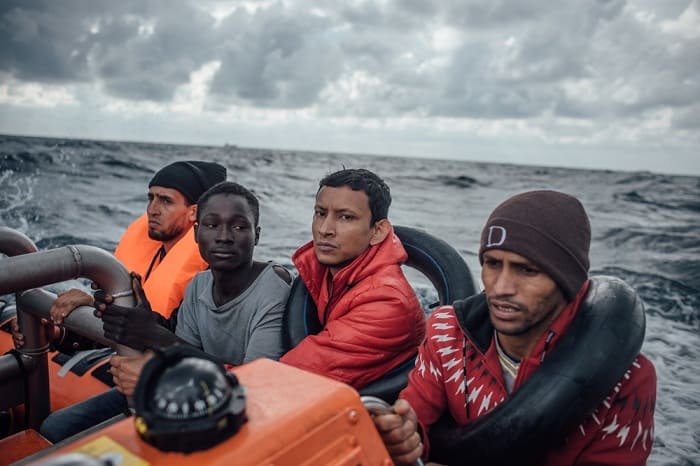 10 | MEDITERRANEAN SEA – KEVIN MCELVANEY December 2016 – Young men hold on tight as a speedboat transfers them from their wooden boat to the MSF/SOS search and rescue vessel, Aquarius, in the rough seas of the Mediterranean, off the northern coast of Libya.