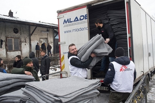 Igor Kuhar, center, and Goran Bakic, right, Medecins Sans Frontieres (MSF) staffers, unload blankets from a truck while distributing aid to refugees in Belgrade, Serbia