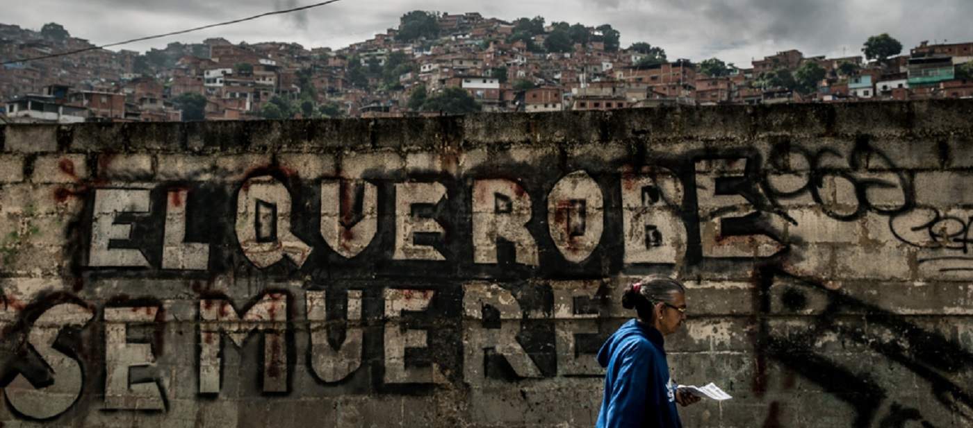 A woman walks through the district of Petare, Caracas, considered to be one of the most dangerous neighbourhoods in Latin America. The graffiti on the wall reads “Anyone who steals will die”. Photo: Marta Soszynska/MSF