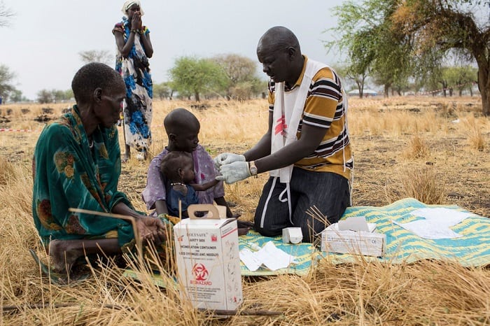 March 2017 – Community Health Promoter, Gatbel, tests a child for malaria at an outdoor support clinic in Thaker, Leer County, South Sudan.
