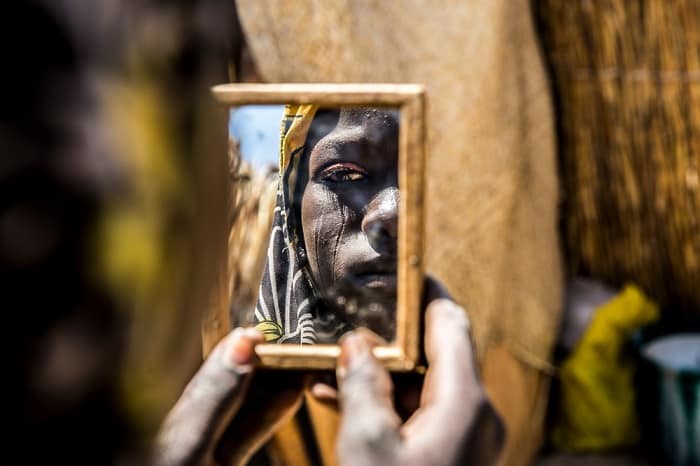 A woman attending an MSF pre-natal clinic in Diffa, Niger, stares back at her reflection in a handheld mirror.