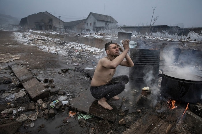 A man washes outdoors using a plastic bottle at a disused warehouse complex in Belgrade, Serbia. Many hundreds of refugees making their way across Europe have sought shelter from the freezing temperatures of the Serbian winter, as their journeys are thwarted by stricter border controls.