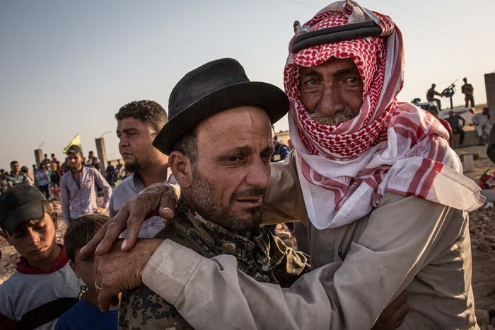 Two men embrace each other, tears in their eyes, during a funeral in Tal Abyad for local men who had fought and been killed in the fight for Raqqa.