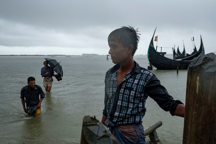 A local Bangladeshi boy watches the Rohingya refugees arriving under torrential rain at a border crossing on the Naf river, near Teknaf, after fleeing Myanmar. More than 600,000 Rohingya have fled to Bangladesh from Rakhine State in Myanmar following an escalation in violence in August.