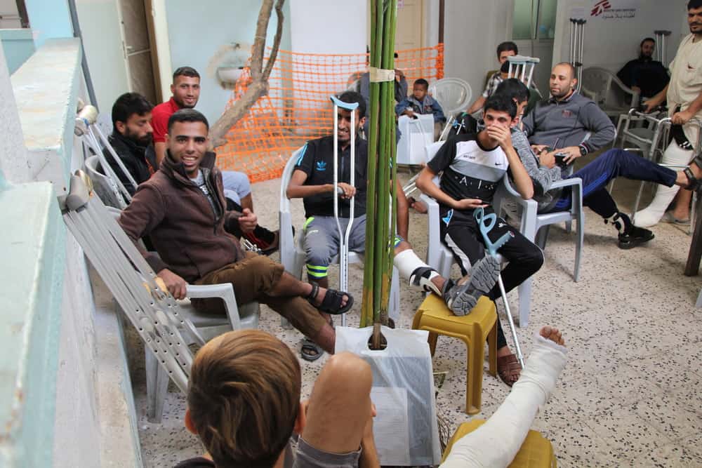 Waiting area of MSF Gaza clinic, full of trauma patients with crutches and wheelchairs.