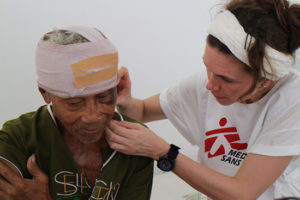 An MSF staff member stitches the wound of a patient with a deep head injury at the clinic in Guiuan. Philippines 2013 © Caroline Van Nespen/MSF