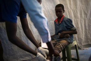 A boy watches while an MSF nurse cleans his infected wound at a displaced persons' camp in Juba. © Phil Moore