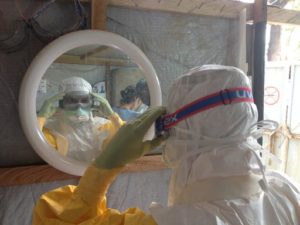 MSF nurse Lucie Perardel checks her goggles, part of the personal protective equipment used by MSF staff when they go into the area with patients who are either suspected or confirmed as having Ebola. &copy;Sam Taylor/MSF