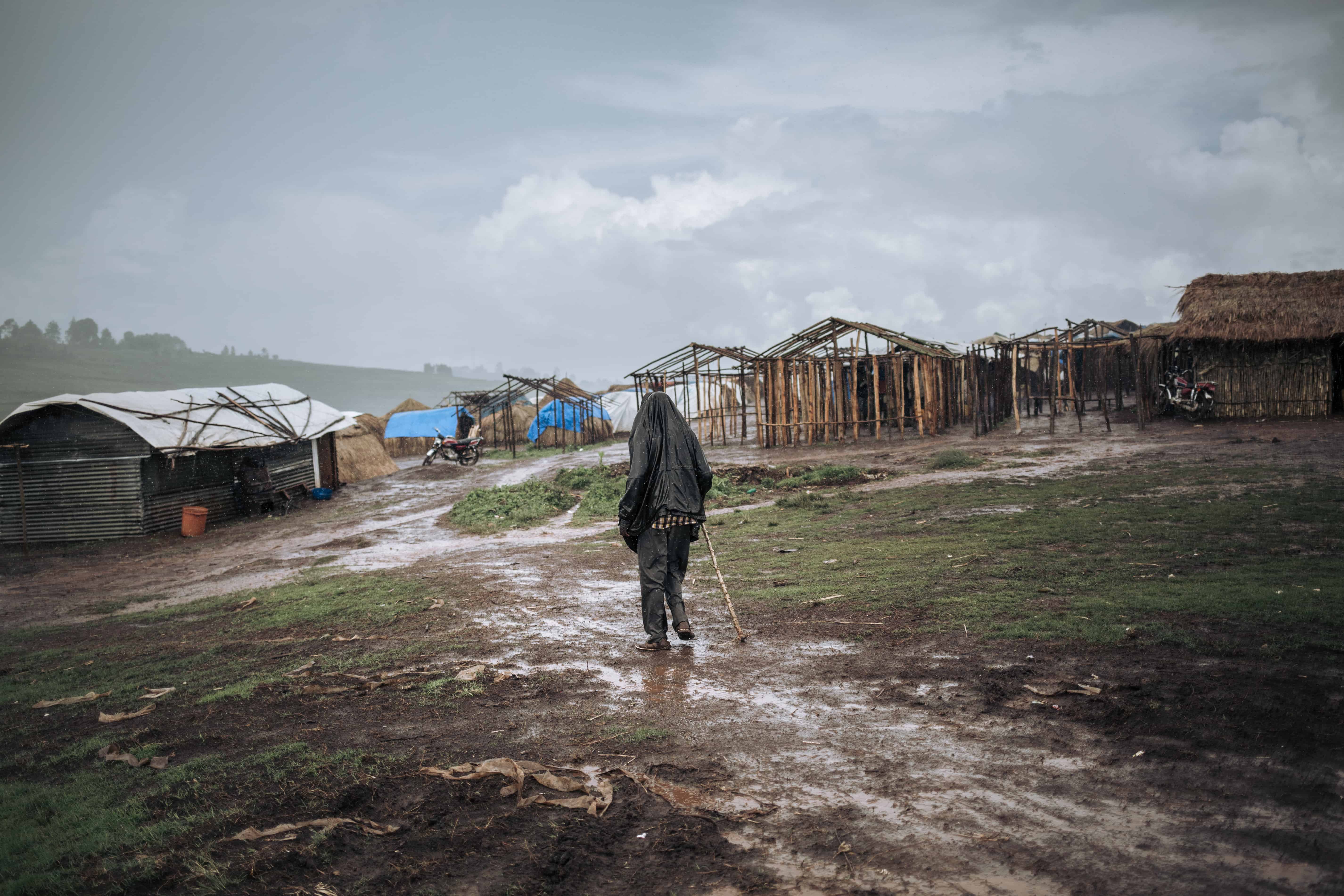 A man walks in the rain in Rho camp, DRC, November 2019. © ALEXIS HUGUET
