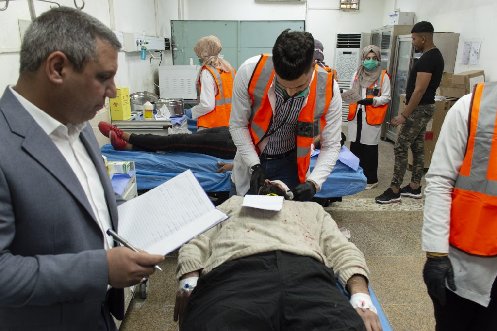 A simulated patient being examined by a nurse during a mass casualty simulation at Al-Hakim General hospital in Najaf governorate, while an observer (on the left) is taking notes about the steps. The simulation was planned and supervised by MSF in collaboration with the directorate of health. Iraq, February 2020. ©MSF/HASSAN KAMAL AL-DEEN