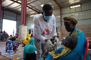 An MSF nurse aide Barnaba performs the MUAC measurement test on a child during a screening in an MSF mobile clinic at the Riverside transit site in Renk town, Upper Nile State, South Sudan.