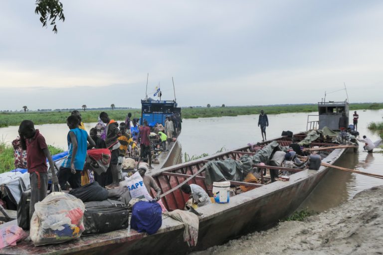 Newly arrived, men, women and children,  arriving from Renk offload their luggage from a boat in Bulukat port in Malakal, Upper Nile State in South Sudan. The Bulukat transit centre hosts over 5,000 returnees who fled the conflict in Sudan.