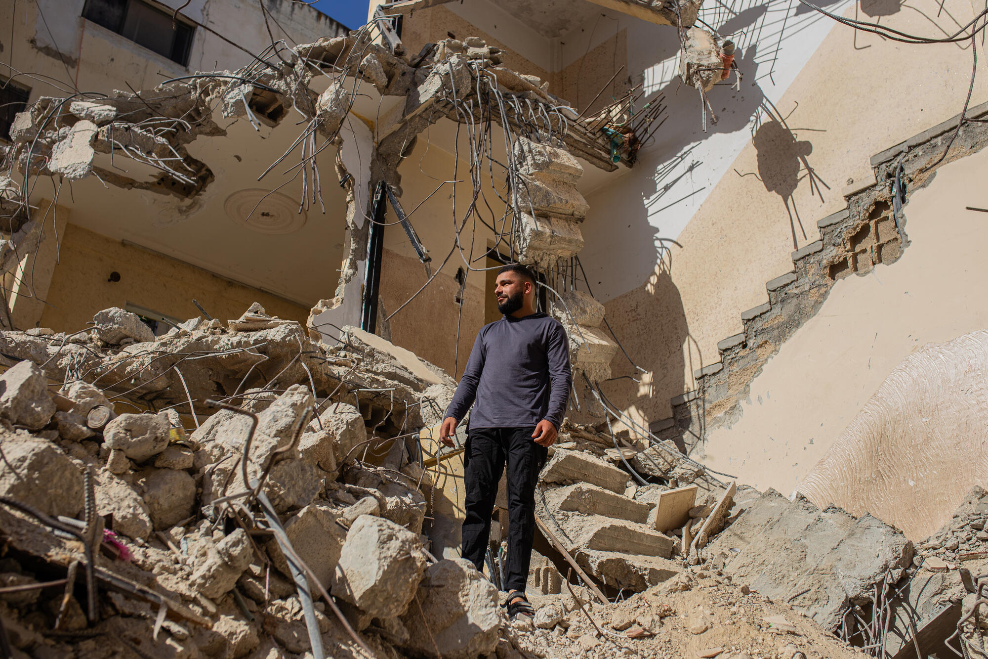 Omar stands in the rubles of his home after it was bulldozed by Israeli forces in Jenin refugee camp. His phone is covered by the pictures of his cousin, killed in a previous incursion.