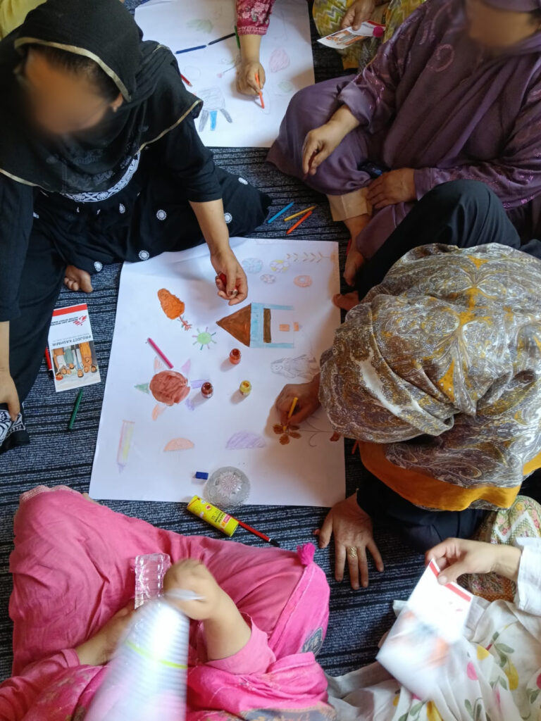 Community members join an art therapy session run by Doctors Without Borders India/Médecins Sans Frontières(MSF) at of the primary health centre in Kashmir, drawing together on a shared page to foster connection and emotional expression. ©MSF
