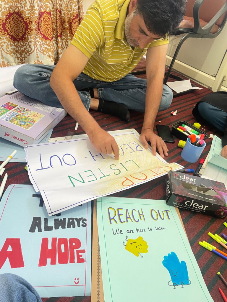 A Doctors Without Borders India/Médecins Sans Frontières(MSF) community mental health worker finishes painting posters reading "Reach Out, we are here to listen" and "There is always hope" for MSF's World Suicide Prevention Day activities in Kashmir. ©MSF