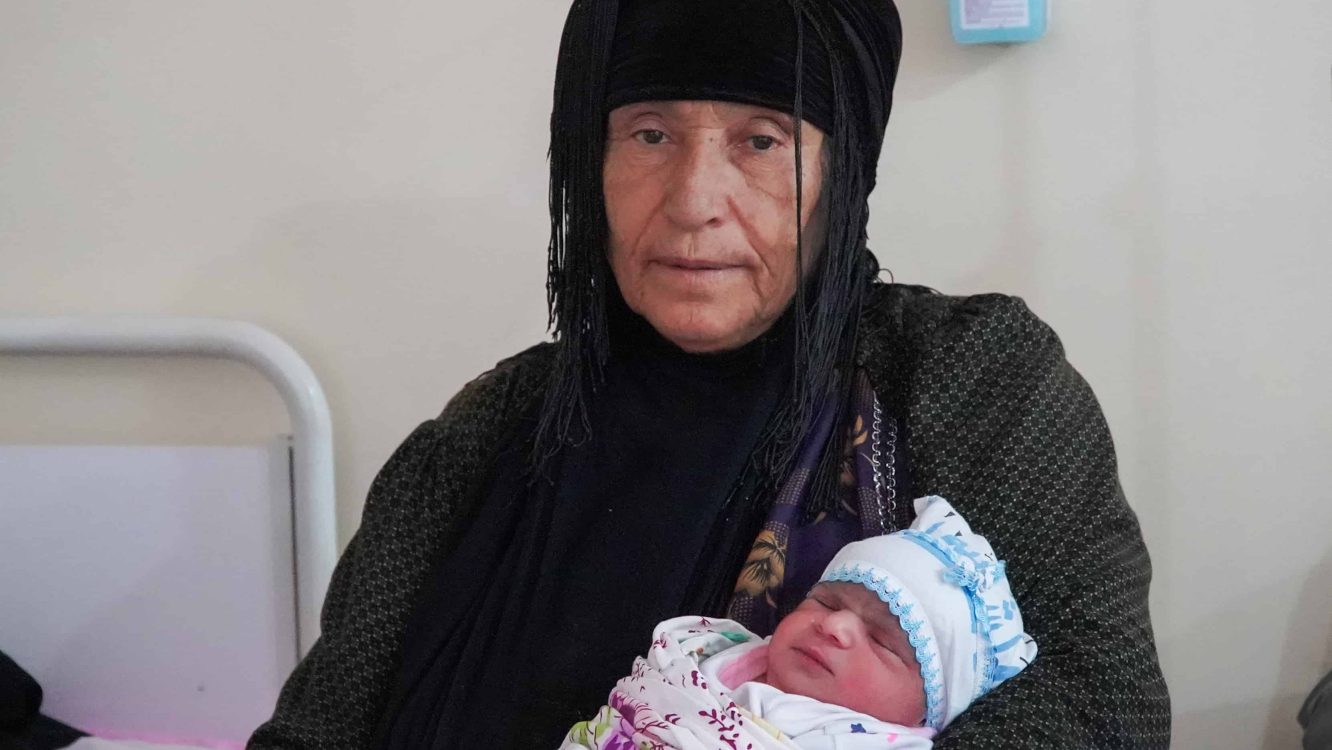 A newborn in the arms of his grandmother in Nablus maternity run by MSF in Mosul.